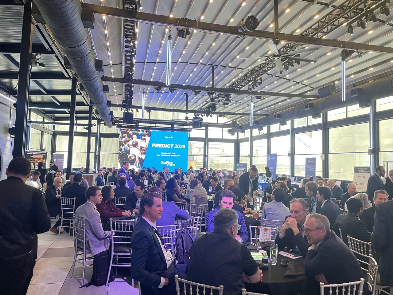 Conference attendees seated at tables under the glass roof at The Rooftop at the Edison
